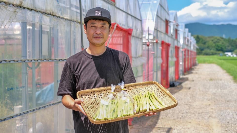 かごに入ったアスパラガスを抱える永田さん